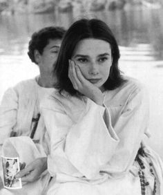 a black and white photo of two people sitting next to each other with their hands on their chins