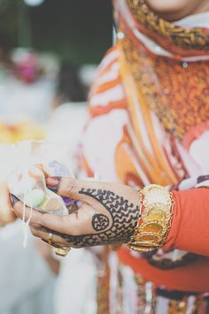 a close up of a person holding something in their hand with henna on her arm