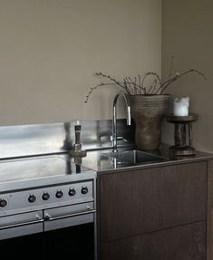 a kitchen with an oven, sink and counter top next to a vase filled with flowers