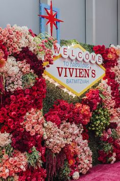 a sign that is on the side of a building with flowers in front of it