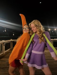 two women are posing for a photo on a pier at night with their arms around each other