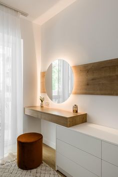 a white room with a round mirror on the wall and a stool in front of it