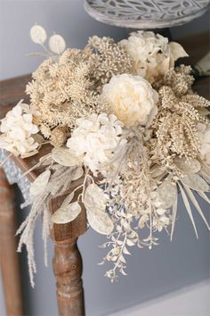 a bouquet of white flowers sitting on top of a wooden table next to a chair