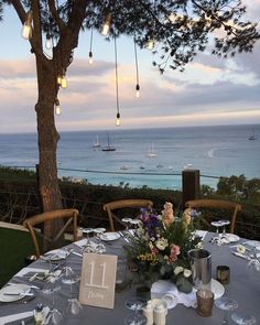 a table set up with place settings for dinner overlooking the ocean and boats in the water