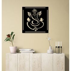 a black and white ganeshi painting on a wall above a cabinet with vases