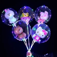 a bunch of hello kitty balloons are in the air with some lights on them and teddy bears