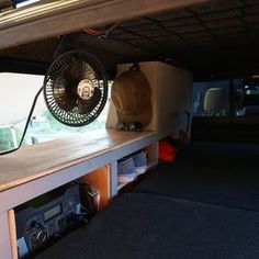 a fan sitting on top of a shelf in the back of a vehicle with other items