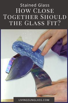 someone is making a glass flower out of the bottom of a piece of blue paper