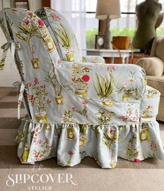 an upholstered chair with flowers and plants on it in front of a window