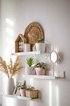 three white shelves with plants and pictures on them