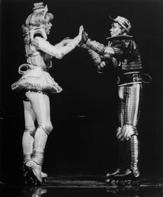 two people dressed in costumes standing next to each other on roller skates, one holding the hand of another person's arm