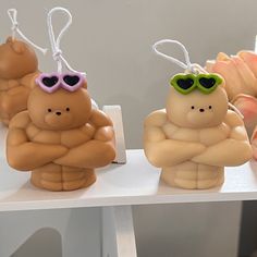 three small plastic figures with sunglasses on their heads and arms are sitting on a shelf