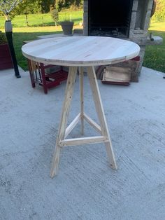 a wooden table sitting on top of a cement floor next to a fire place in a backyard