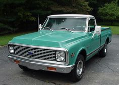 an old green pickup truck parked in a parking lot