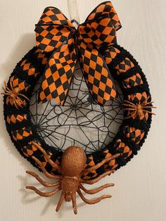 an orange and black wreath with spider decorations on the front, hanging on a wall