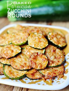 baked parmesan zucchini rounds on a plate with cucumbers in the background