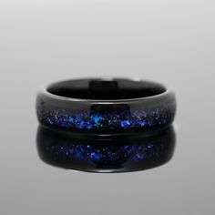 a ring with blue and black speckles is shown on a reflective table top