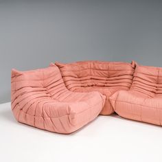 a large pink couch sitting on top of a white floor next to a gray wall