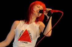 a woman with red hair singing into a microphone