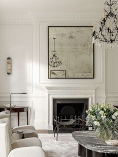 a living room filled with furniture and a chandelier hanging from the ceiling over a fire place