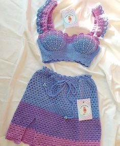 a crocheted baby outfit and diaper cover on a white sheet with a tag