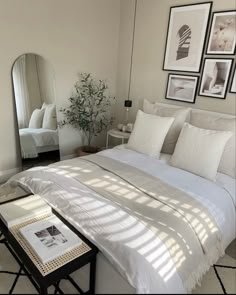 a bedroom with white bedding and pictures on the wall