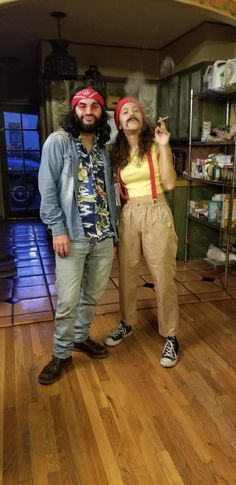 a man and woman dressed up in costumes standing next to each other on a hard wood floor