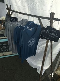 several t - shirts are hanging on a clothes rack outside in front of a tent