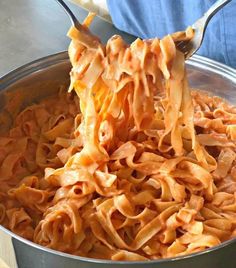 a spoon full of pasta being lifted from a pot with the noodles in it to be eaten