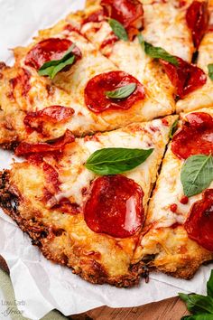 two slices of pepperoni pizza on top of white parchment paper with green leafy garnish