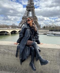 a woman is sitting on the wall in front of the eiffel tower