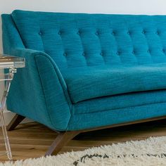 a blue couch sitting on top of a hard wood floor next to a white rug