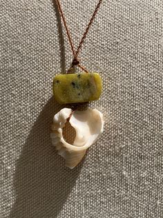 a shell with a piece of food in it on a string necklace that is attached to a leather cord