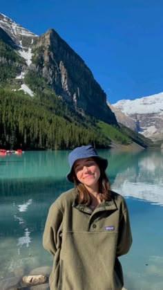 a woman standing in front of a mountain lake