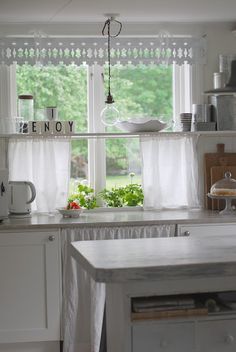 a kitchen with white cabinets and an island in front of a window that has the words eat enjoy written on it