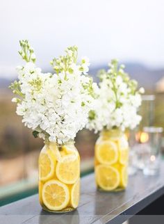 three mason jars filled with lemons and white flowers