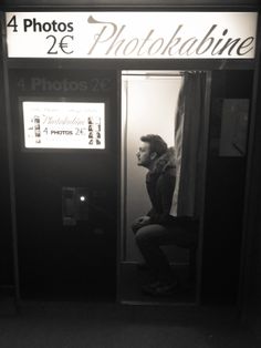 a man sitting on top of a phone booth next to a sign that reads 24 photos