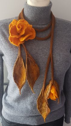 a mannequin with an orange flower and two leaves on it's neck