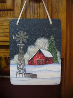 a red barn in the snow with a windmill hanging from it's front door