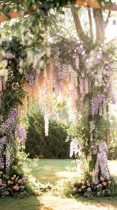 an outdoor ceremony with purple flowers and greenery on the arbor, surrounded by lush green grass