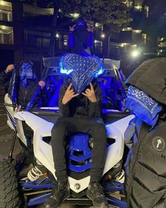 a man sitting on the back of a blue and white four - wheeled vehicle at night