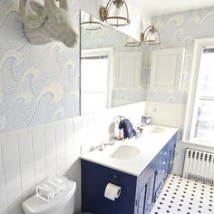 a white toilet sitting next to a blue sink in a bathroom on top of a black and white tile floor