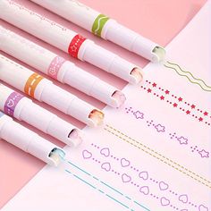 four pens are lined up on top of a piece of paper with hearts and stars