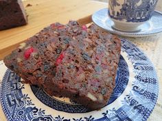 a piece of chocolate cake on a blue and white plate next to a tea cup