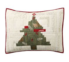 a decorative christmas tree pillow on a white background with red trimmings and an embroidered border