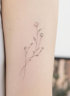 a small flower tattoo on the back of a woman's arm