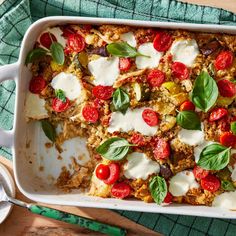 a casserole dish with tomatoes, mozzarella and basil leaves on top