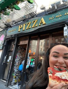 a woman eating a slice of pizza in front of a restaurant