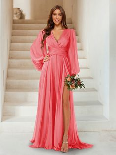 a woman standing in front of stairs wearing a long pink dress with thigh high slit