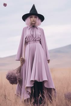 a woman in a purple dress and black hat standing in tall grass with her hands on her hips